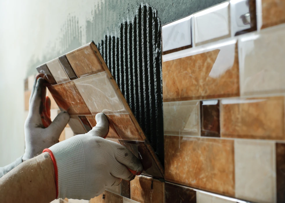Pose de carrelage mural par un artisan carreleur professionnel dans un intérieur résidentiel