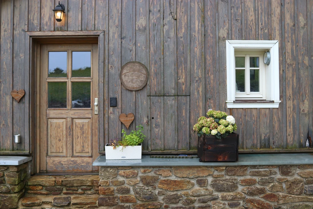 Entrée de maison avec terrasse en pierres naturelles rouges présentant de multiples fissures et dégradations