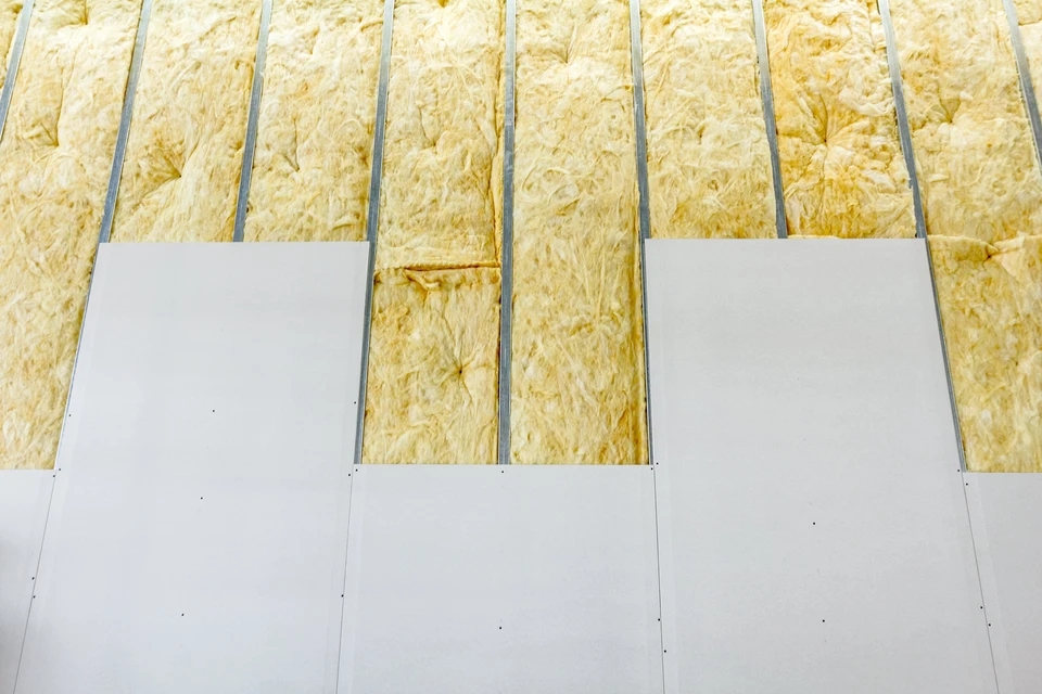 Ouvrier en bâtiment installant de l'isolation thermique dans une construction résidentielle